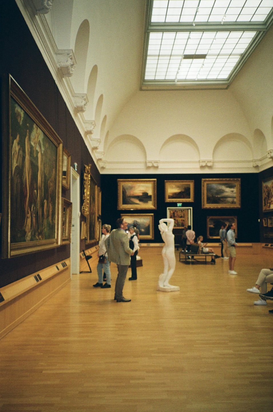 Persone che ammirano arte classica e sculture in un grande museo.