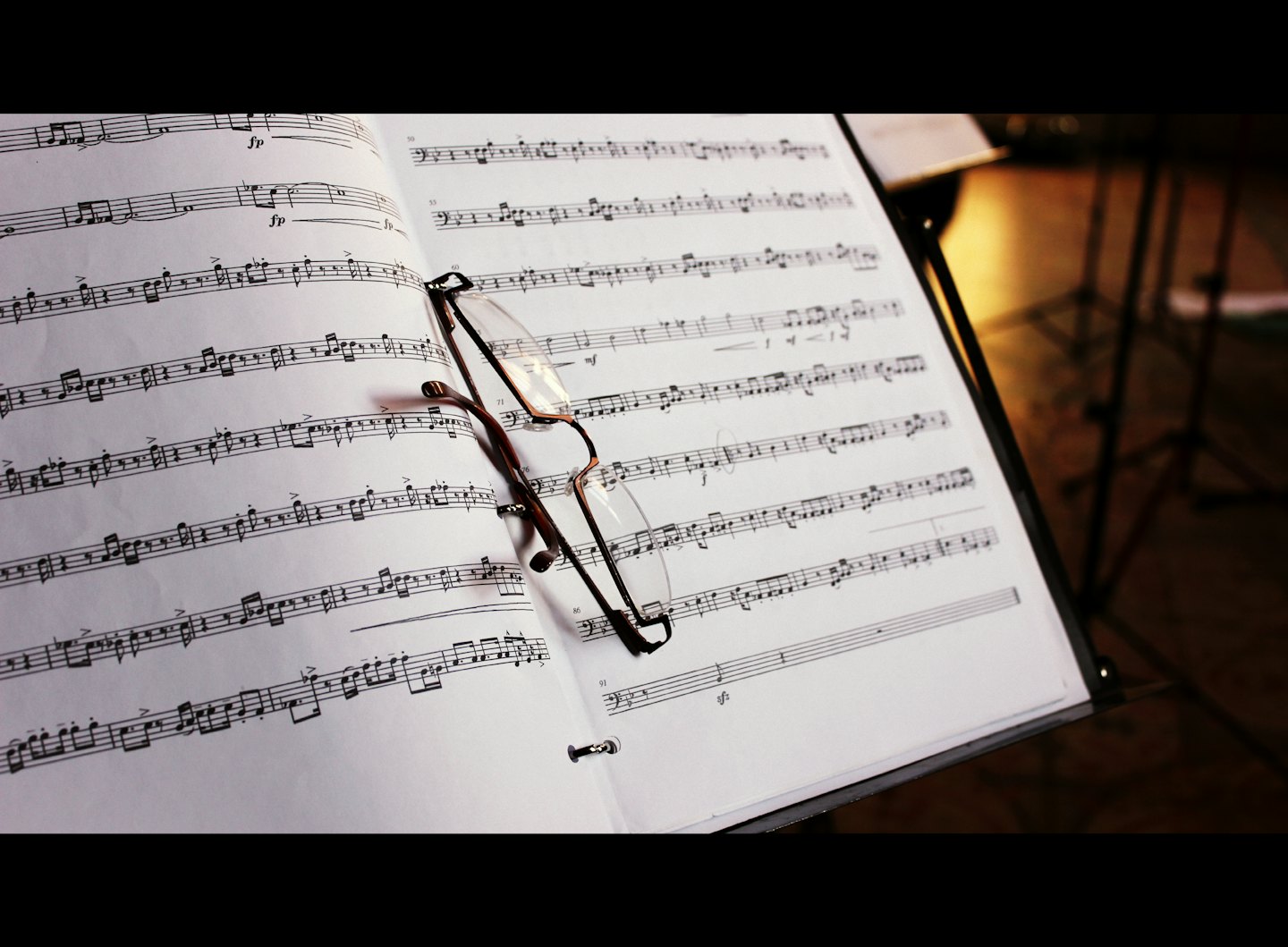 Occhiali da lettura appoggiati su un libro aperto di spartiti musicali.