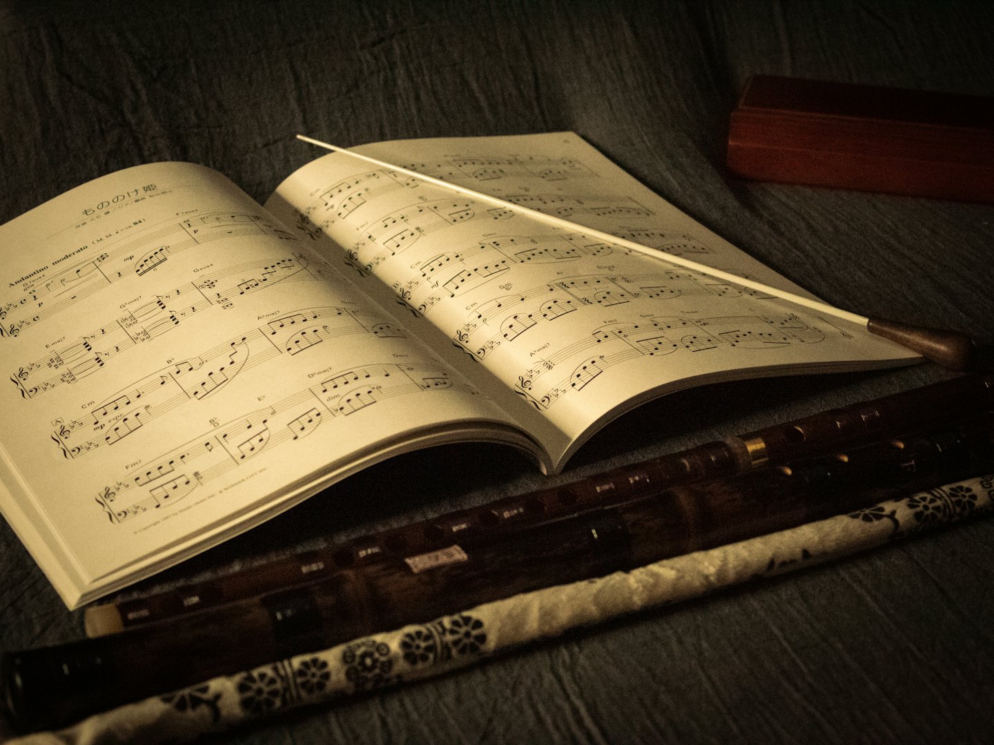 Spartito musicale, bacchetta e due flauti in una custodia.