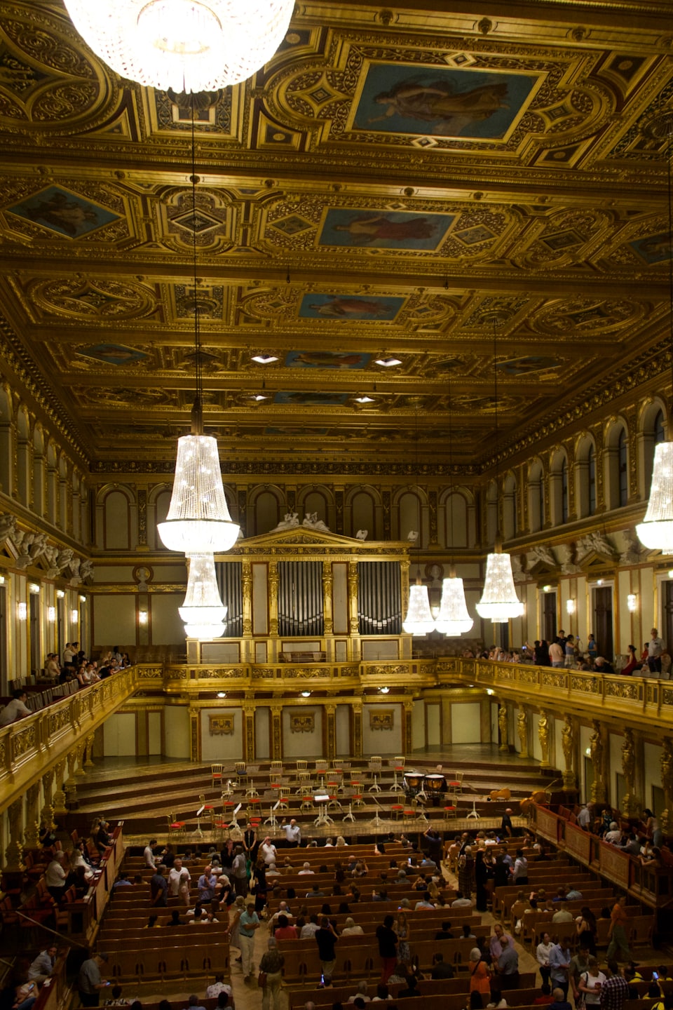 Folla riunita in un'ornata sala da concerto con balconi dorati.