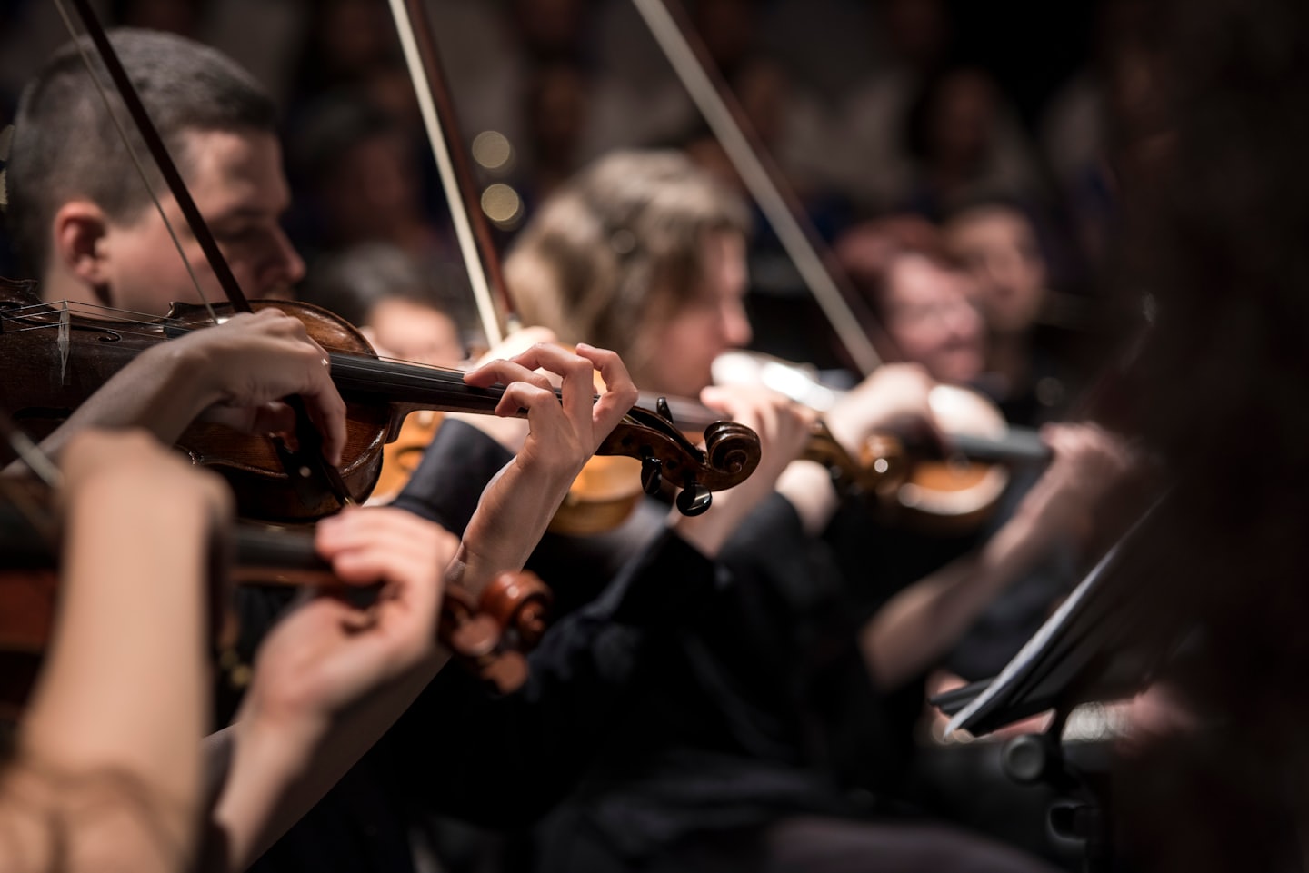 Mani di musicisti che suonano violini in legno con archi.